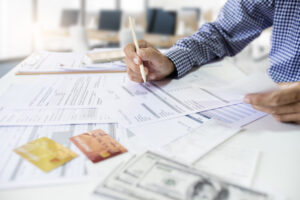 Asian man working in office checking purchase order and financial bills. calculate expenses and business cost to be pay after use credit card