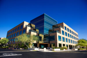 Stunning Scottsdale Arizona business building on blue backgrounded sky with matching blue glass windows beautifully landscaped with desert tolerant plant and trees on a clear day with set on a bright blue clear sky background.