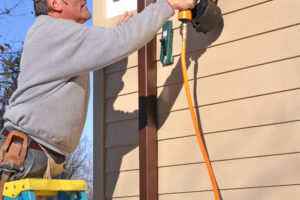 Man installing fibrous cement siding with nail gun